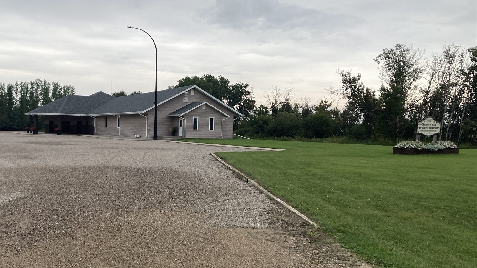 The church building on Castleton Road, with its gravel parking lot, lawn and sign, surrounded by trees